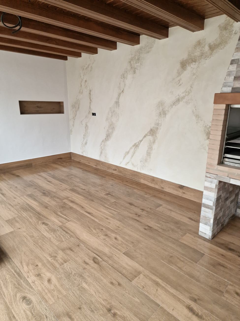 Pared con efecto mármol veteado en un salón con vigas de madera